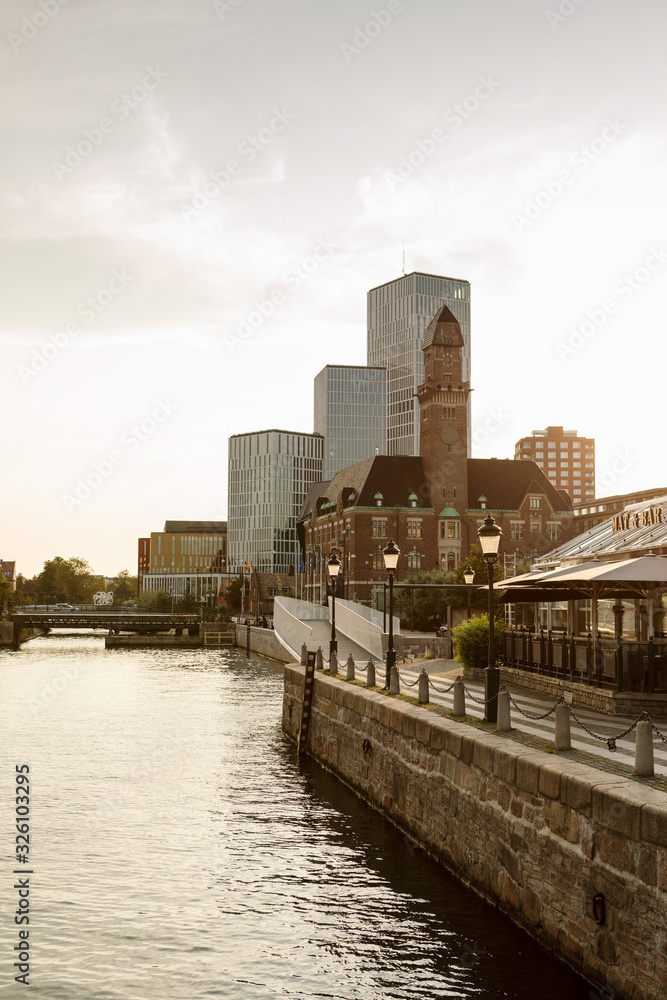 Buildings by river against sky in city during sunset Buildings by river against sky in city during sunset