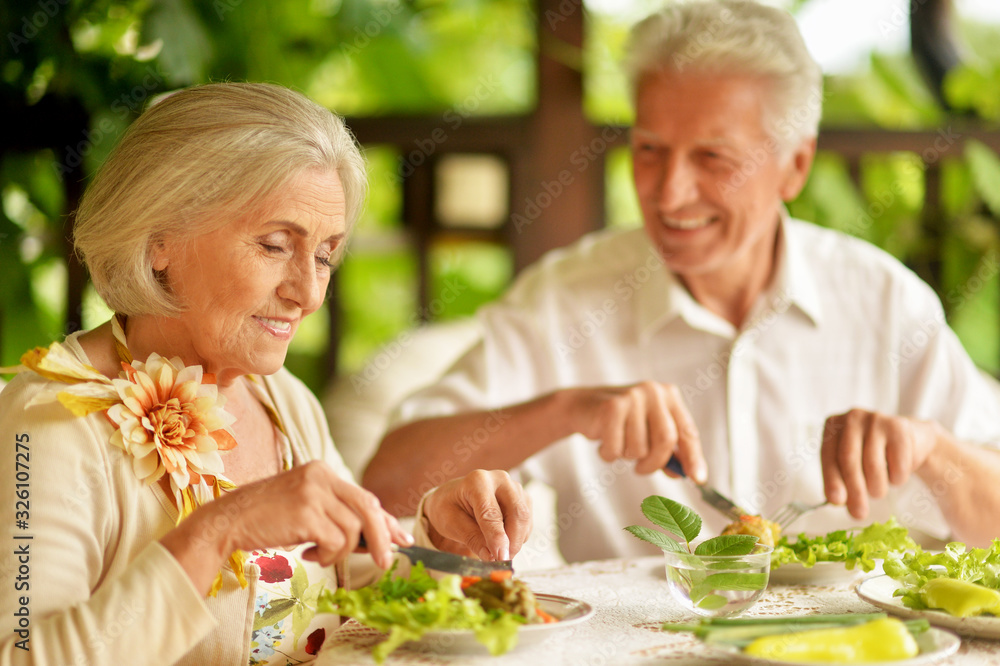 Portrait of happy senior couple having diner and posing on the veranda