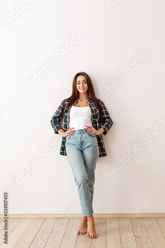 Portrait of a young beautiful brunette woman in casual clothes posing on a white background. Copy space. Vertical orientation