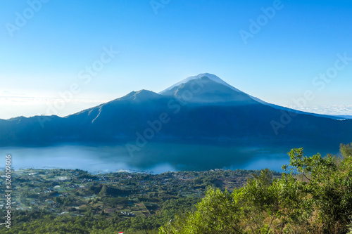 An idyllic view from the top of Mount Batur on Mount Agung and the Danau Batur lake. There is a pathway along Batur volcano's rim. Volcanic landscape of Bali, Indonesia. Island hiking.