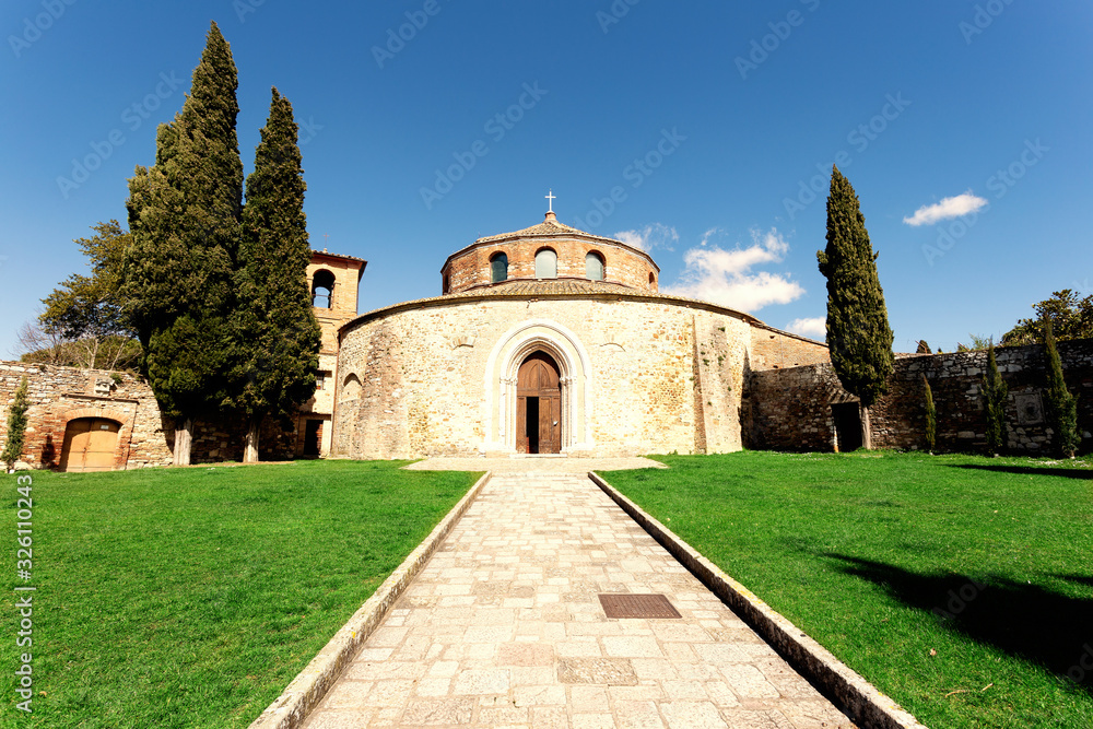 Perugia, Italy - March 3, 2016: The small temple. External photo of the Church of San Michele Arcangelo, with the path that cuts the green lawn and the cypresses on the sides. Clear blue sky with smal
