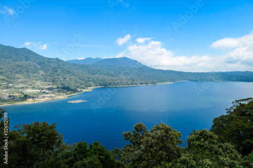 A panoramic view on The Twin Lake, Bali, Indonesia. The lake is surrounded by lush green plants. There are small hills all around the lake. Touristic attraction. Biggest lake on Bali © Chris