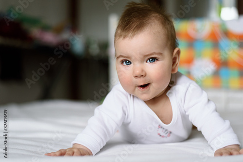closeup smiling blue-eyed baby in white bodysuit