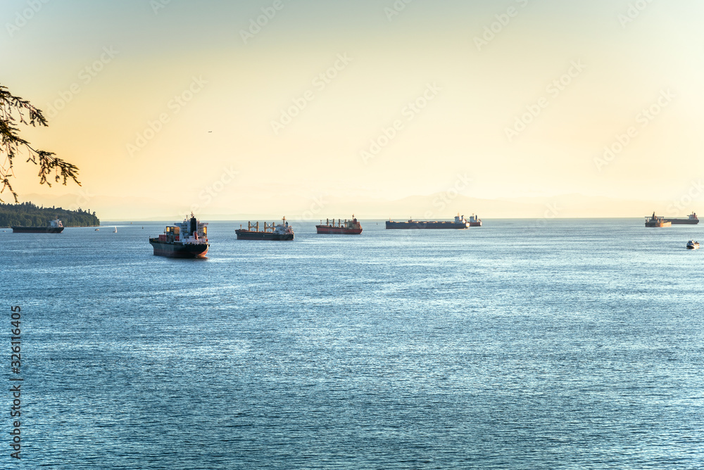 Cargo ships anchored in a bay at sunset. English bay, Vancouver, BC, Canada.