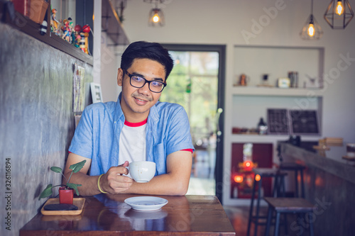 Attractive Asian man drinking coffee at the table in coffee shop. Film tone effected.