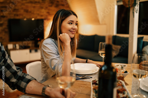 Young smiling woman during dinner at dining table.