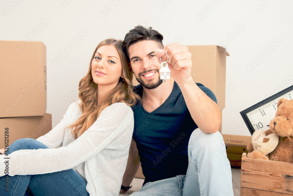 Young couple holding their new house keys Young couple holding their new house keys