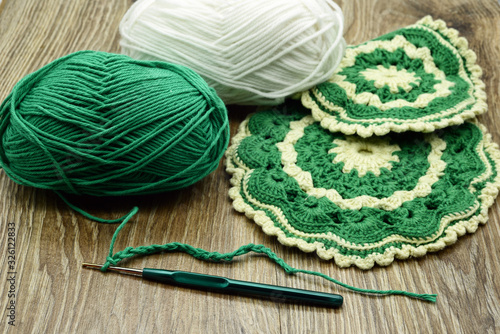 traditional crochet oven gloves made of green and beige wool.