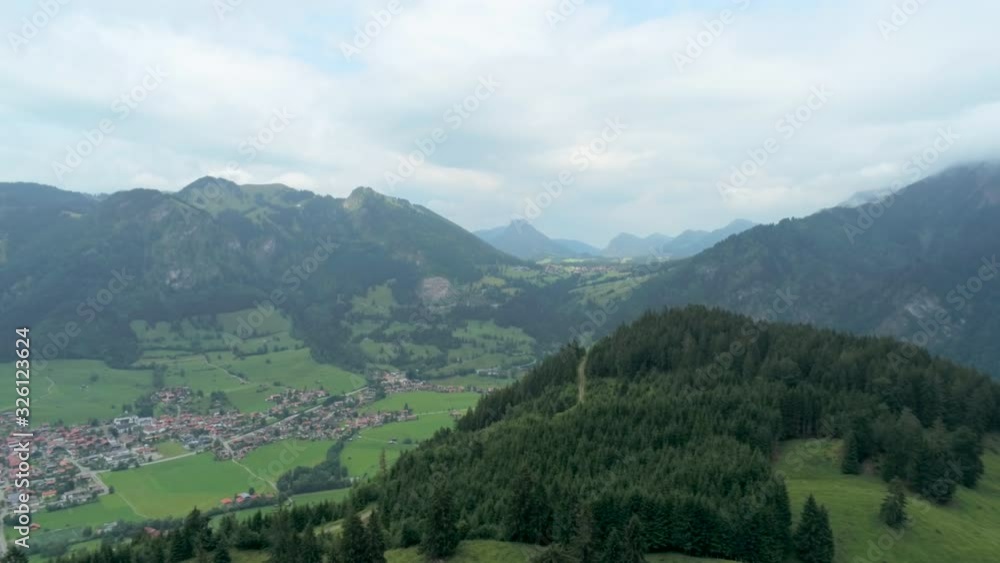 Majestic Aerial View of Village in Alps Mountains. Alpine Countryside with River, Forest and Car road. Nature, Agriculture and Ecotourism in Germany, Europe. 4K Drone Long Pull in Shot Majestic Aerial View of Village in Alps Mountains. Alpine Countryside with River, Forest and Car road. Nature, Agriculture and Ecotourism in Germany, Europe. 4K Drone Long Pull in Shot
