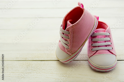 Pink baby girl shoes, on gray background. Newborn, motherhood, pregnancy concept with copy space. © Inga