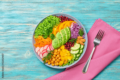 Buddha bowl salad with avocado, tomato, lettuce, cucumber, red cabbage, chickpeas, pomegranate. Paleo diet, healthy vegan and balanced food concept. Fresh rainbow mix green salad on wood