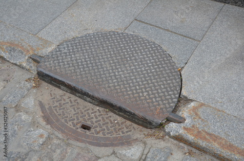 curb with sewer or manhole cover and sidewalk