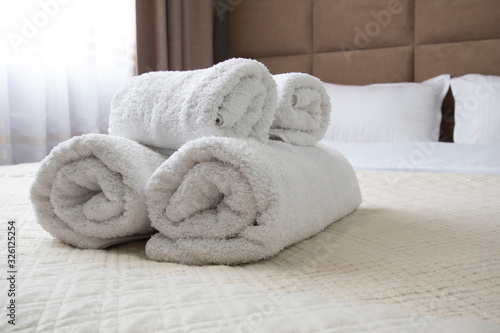 Clean white rolled towels on the bed. Close-up © Denis