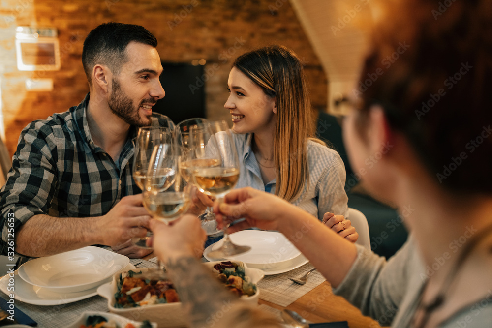 Young happy couple toasting with wine while having dinner with friends. Young happy couple toasting with wine while having dinner with friends.