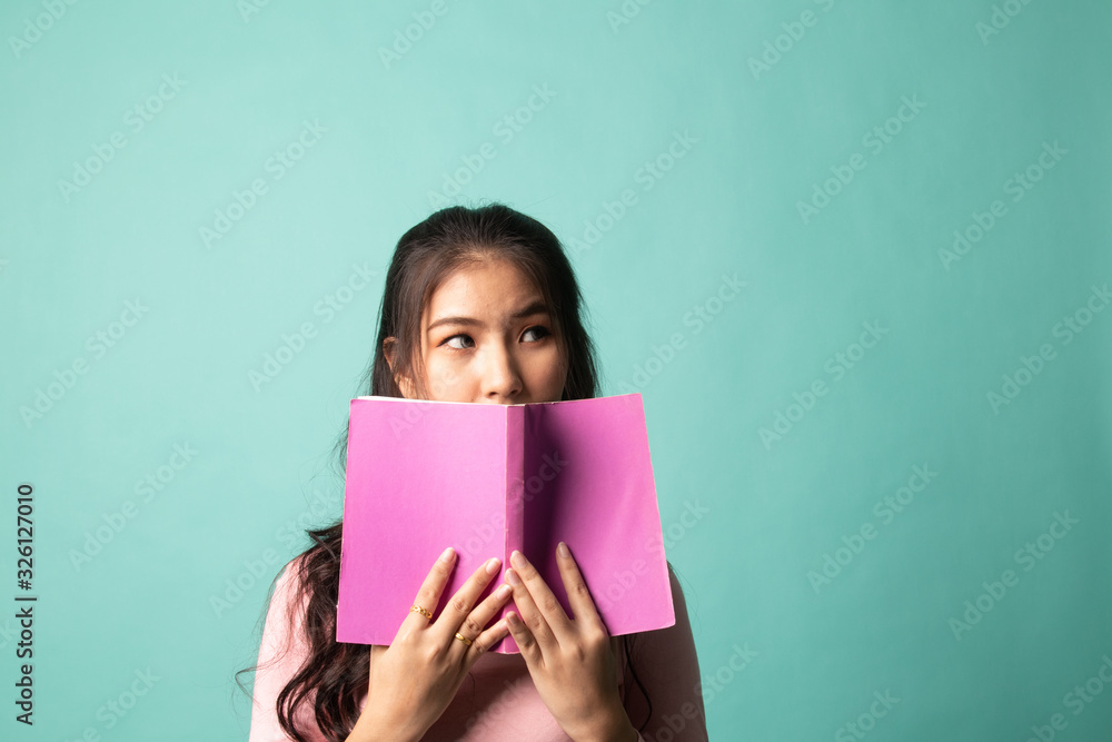 Young Asian woman with a book cover her face.