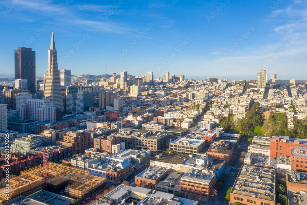 San Francisco aerial view of downtown at sunrise. Drone view facing downtown. Blue sky, golden light copy space in sky. Embarcadero and North Beach area in foreground.