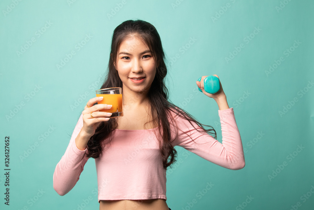 Young Asian woman with dumbbell drink orange juice. Young Asian woman with dumbbell drink orange juice.