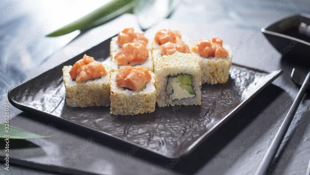 Delicious Japanese sushi food. Rotation view of appetizing white sushi rolls with avocado, raw fish meat slices, sesame seeds. Meal served at Asian restaurant. Healthy eating concept. Delicious Japanese sushi food. Rotation view of appetizing white sushi rolls with avocado, raw fish meat slices, sesame seeds. Meal served at Asian restaurant. Healthy eating concept.
