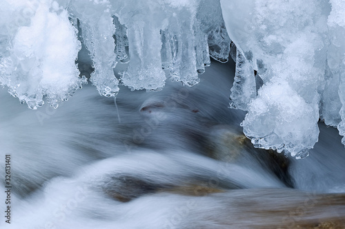 Winter stream captured with motion blur and framed by icicles, Orangeville Creek, Michigan, USA
