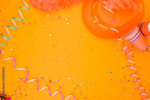 Decor for a traditional celebration of King's Day in the Netherlands. Carnival decorations on a yellow background. A free place for text. Flat lay.