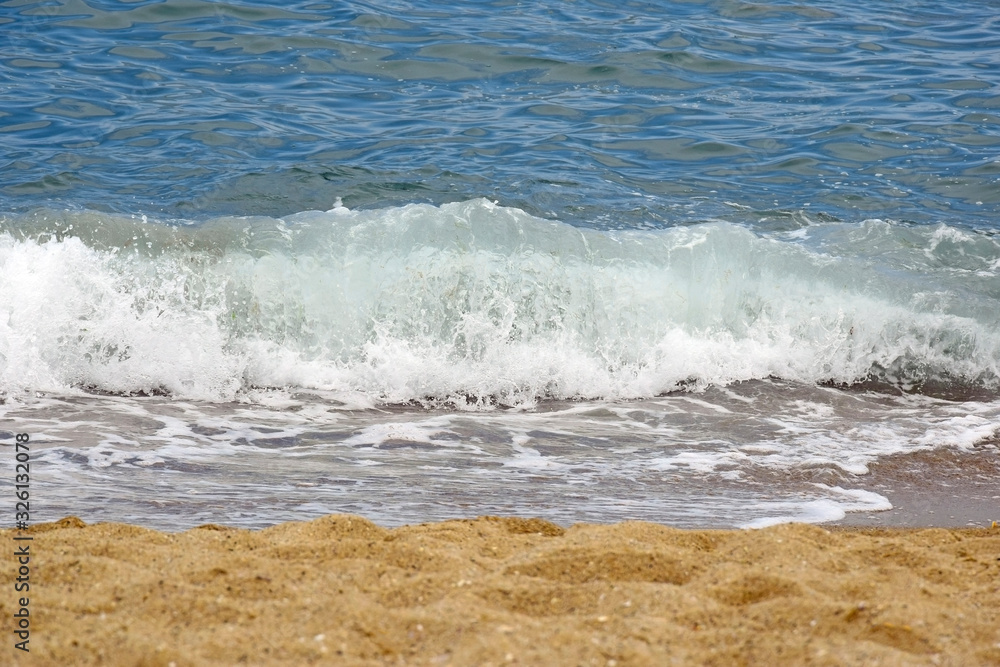Sea wave rolls on the coastline of a sandy beach, summer holiday, vacation.