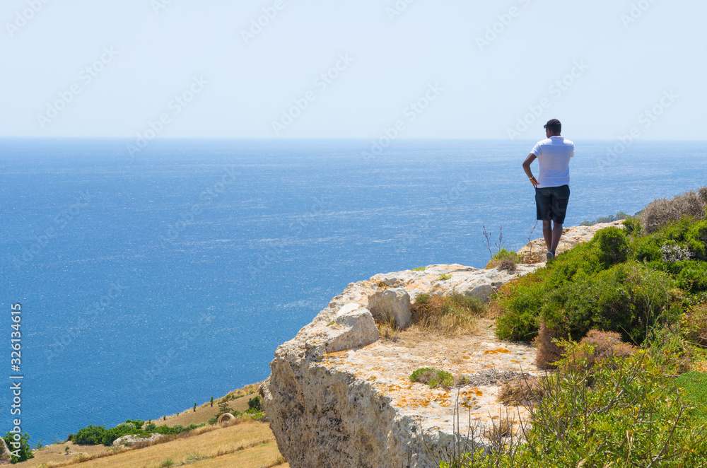Tourist on a cliff overlooking the vast Mediterranean Sea off the coast of Malta at Mellieha 