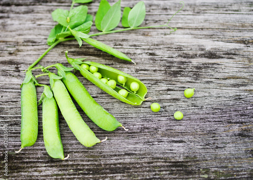 Fresh green pea pods on a rough wooden old surface, top view, copy space