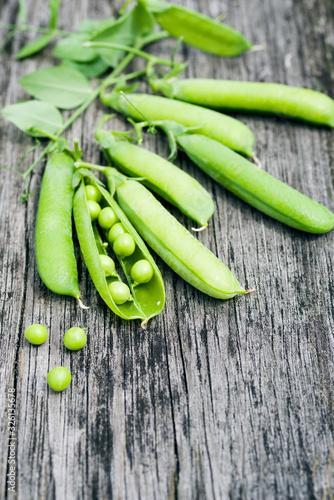 Fresh green pea pods on a rough wooden old surface, copy space