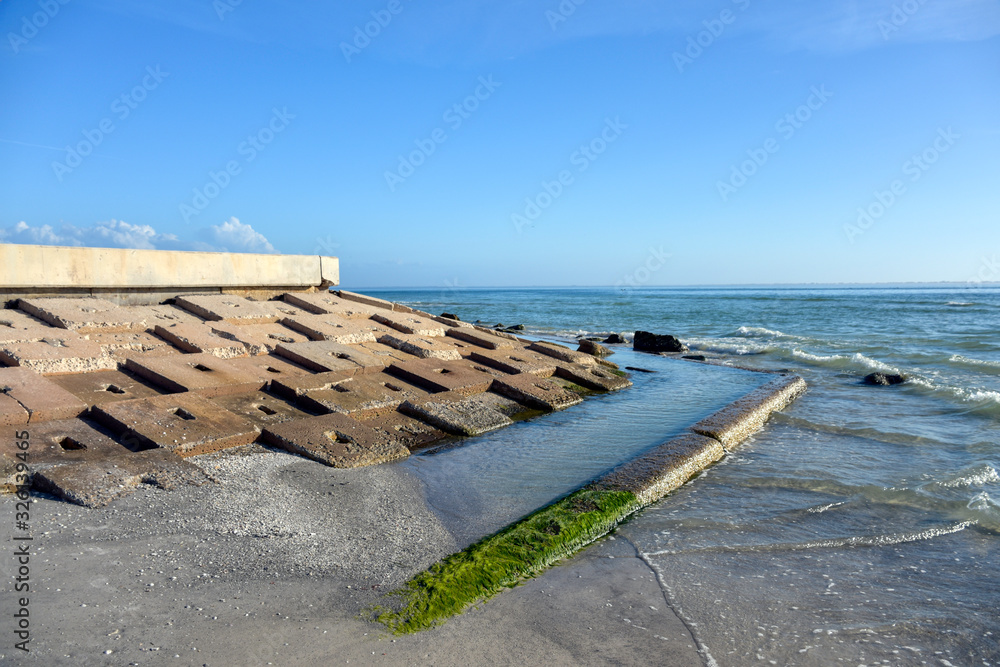 A break wall on a beach in Tampa Bay, Florida suggests rising sea levels and climate change denial.