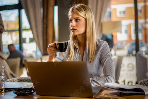 Young attractive woman thinking and holding a cup of coffee