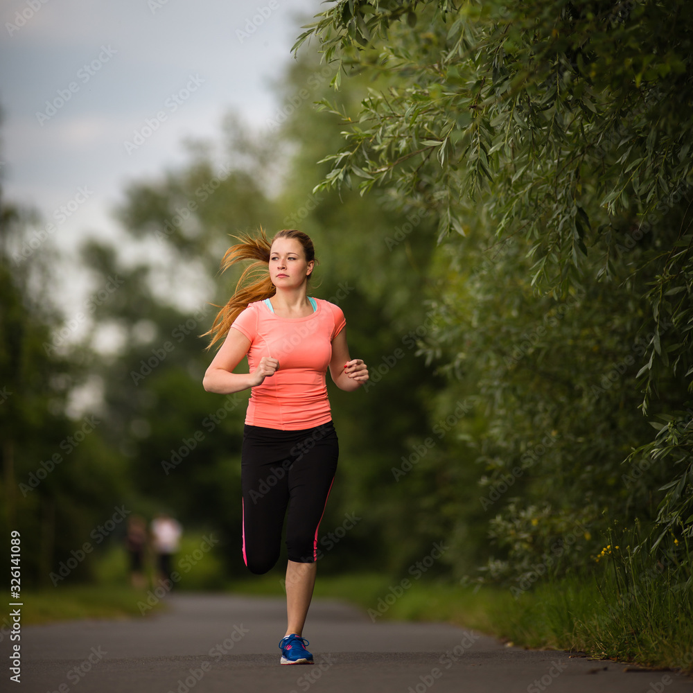 Young woman running outdoors on a lovely sunny winter/fall day (motion blurred image) Young woman running outdoors on a lovely sunny winter/fall day (motion blurred image)