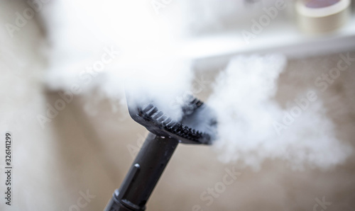 steam cleaner for cleaning the house, steam erupts from the brush. photo