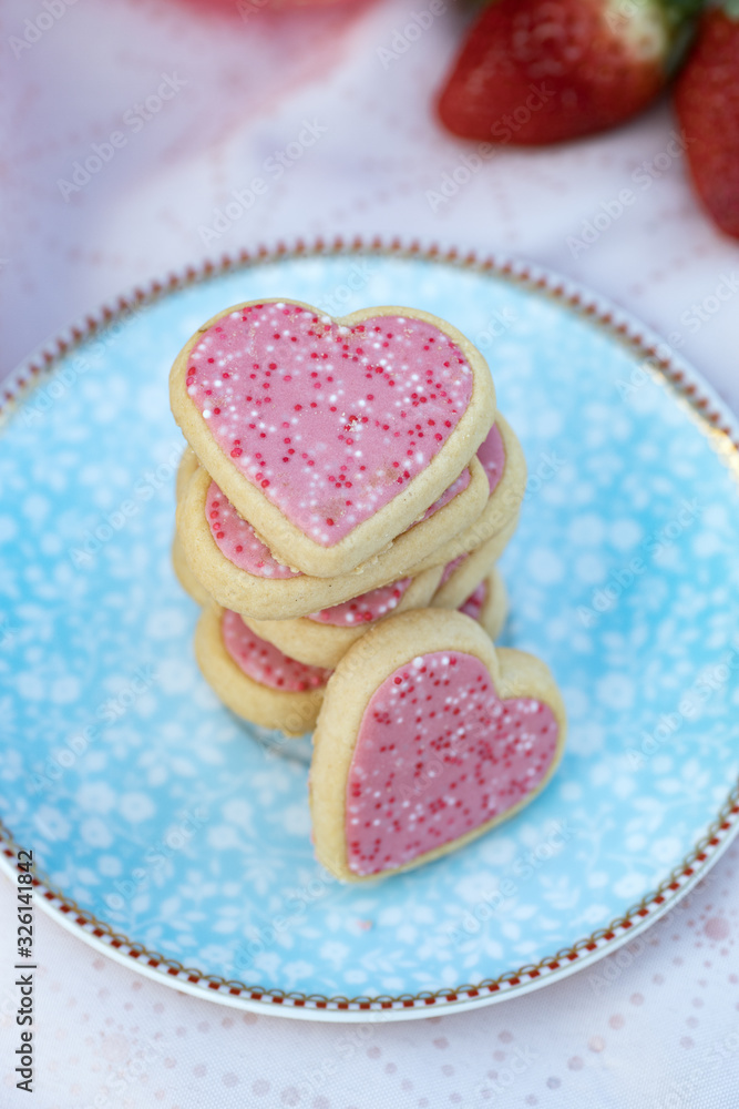 Pink heart-shaped cookies on decorated plate Pink heart-shaped cookies on decorated plate