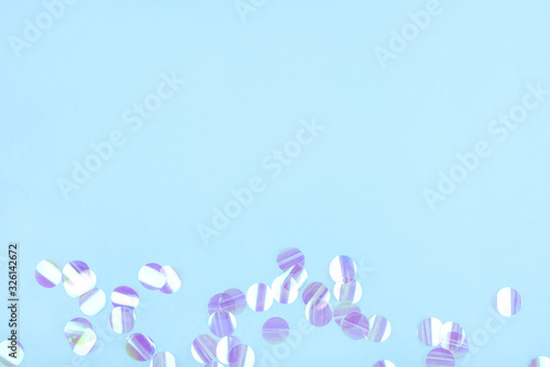 Pearl confetti on blue background. Flat lay, top view.