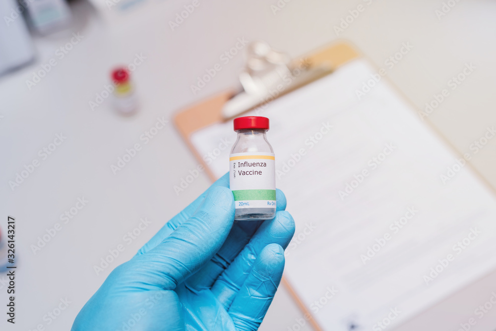 influenza vaccination concept doctor with blue gloves holding vaccine vial and clipboard with checklist in background
