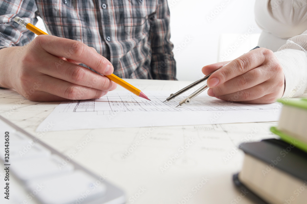 Architects working on blueprint, real estate project. Architect workplace - architectural project, blueprints, ruler, calculator, laptop and divider compass. Construction concept. Engineering tools. Architects working on blueprint, real estate project. Architect workplace - architectural project, blueprints, ruler, calculator, laptop and divider compass. Construction concept. Engineering tools.