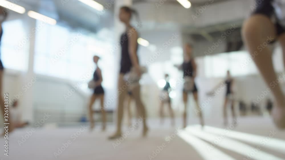 Unfocused shot of unrecognizable teen girls in black outfits holding pom-poms and practicing cheerleading routine Unfocused shot of unrecognizable teen girls in black outfits holding pom-poms and practicing cheerleading routine