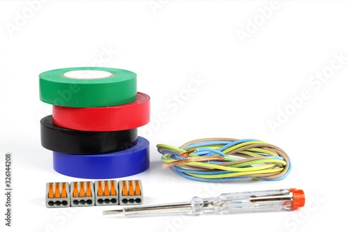 Items for electrical work. Insulating pvc tape for wires, indicator screwdriver, quick-release terminals on a light background.