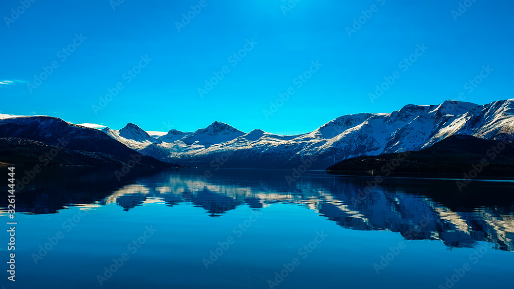 waterreflections infront of snowy mountains and a blue vlear sky