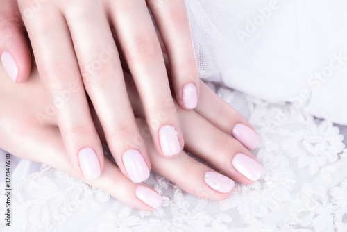 Nude Nail Polish. Beige manicure with pearls on a white background.