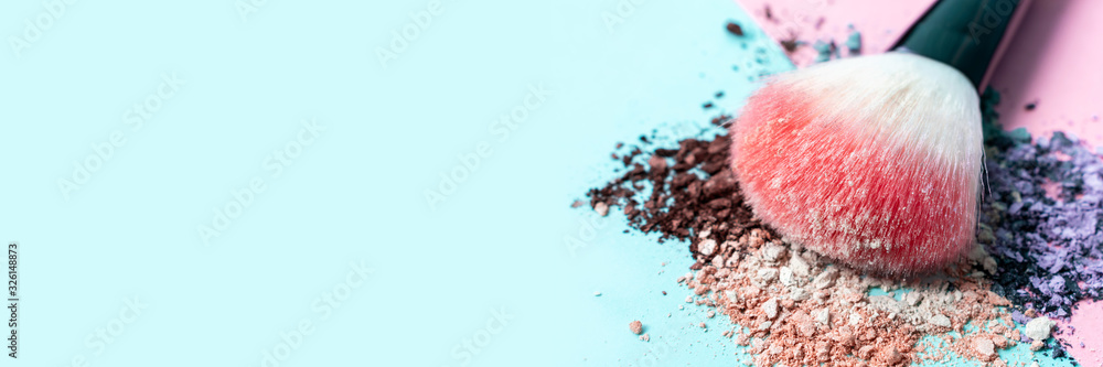 Fototapeta Beautiful bright makeup brush on a trendy pastel pink and blue background. Beauty banner. Cosmetic products. Crumbled multicolored eyeshadow. Place for text and design. Copy space.