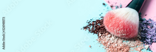 Fototapeta Beautiful bright makeup brush on a trendy pastel pink and blue background. Beauty banner. Cosmetic products. Crumbled multicolored eyeshadow. Place for text and design. Copy space.
