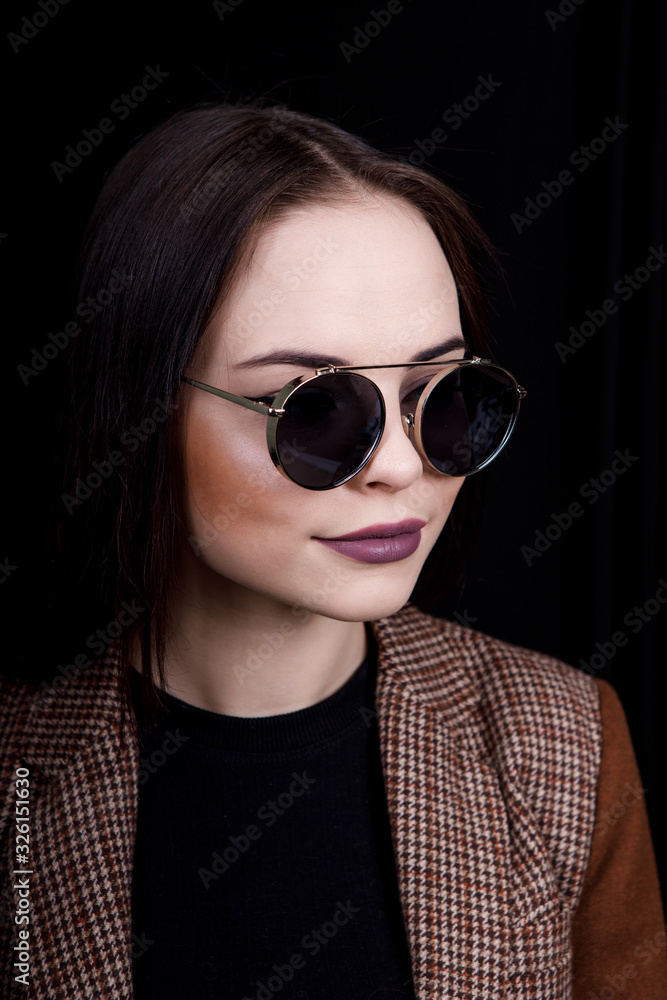 Image of sweet confident young lady standing over black background in studio, wearing pink blouse and fashionable eyeglasses, having long brown hair Image of sweet confident young lady standing over black background in studio, wearing pink blouse and fashionable eyeglasses, having long brown hair