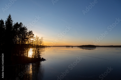 Wintry landscape during sunset in Finland. Cold afternoon in February. Golden hour and reflecting ice and water on the shore.