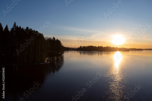 Wintry landscape during sunset in Finland. Cold afternoon in February. Golden hour and reflecting ice and water on the shore.