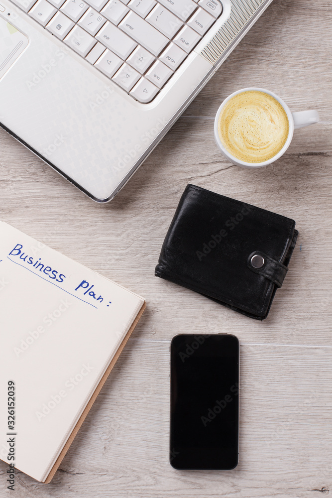 Personal items and cappuccino close up. PC and planner. Wallet and mobile. Minimalism concept. Personal items and cappuccino close up. PC and planner. Wallet and mobile. Minimalism concept.