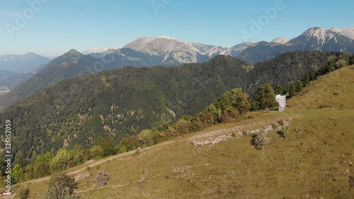 Wallpaper Mural Aerial shot of mountain biker climbing gravel road uphill on grassy slope, mountains and valley in background, summer sunny day with clear sky. Torontodigital.ca