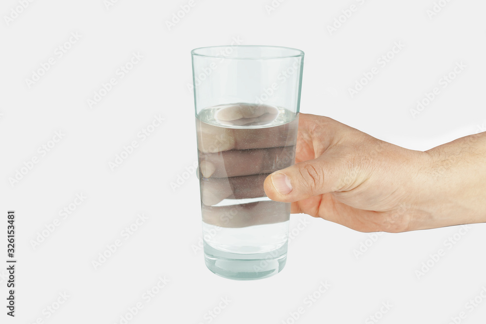 The hand holds a glass of water on a white background. The hand holds a glass of water on a white background.