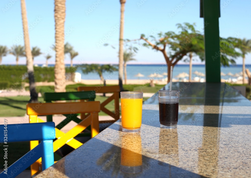 Naklejka premium Two cocktail glasses infront of sea blue water