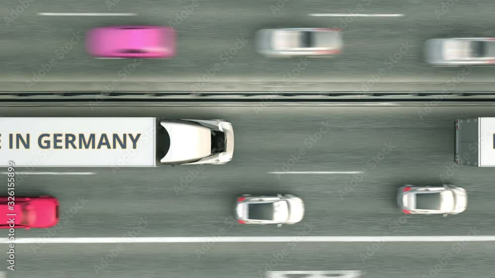 Aerial overhead view of semi-trailer trucks with MADE IN GERMANY text driving along the highway. German business related loopable 3D animation Aerial overhead view of semi-trailer trucks with MADE IN GERMANY text driving along the highway. German business related loopable 3D animation